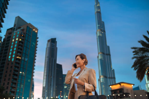 Woman discussing Binghatti Hills warranty and after-sales service while standing in front of skyscrapers.